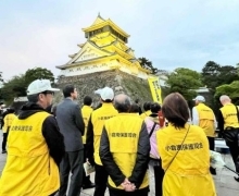 北九州市保護司会連絡協議会の皆さんがイエローライトアップを見守る様子の写真