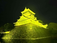 イエローライトアップされた小倉城の写真